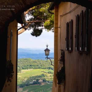 Blick durch eine Gasse auf die umliegenden Hügel von Montepulciano
