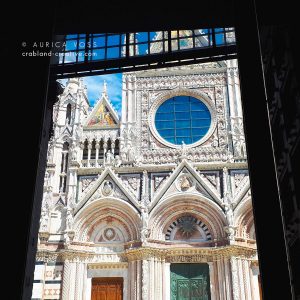 Die Frontseite der Kathedrale von Siena durch eine Tür des gegenüberliegenden Gebäudes